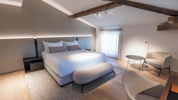 Un dormitorio moderno con una cama grande, mesitas de noche, una silla y una pequeña mesa.