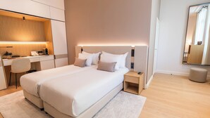 Una habitación de hotel moderna con una cama grande, mesitas de noche, un escritorio y un espejo.