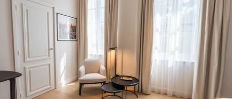 A hotel room with a bed, a chair, a small table, and a picture on the wall.