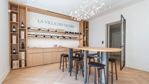Una cocina moderna con un botellero de madera, taburetes de bar y una mesa central.
