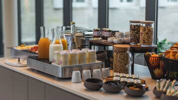 Un buffet de petit-déjeuner proposant une variété d’aliments et de boissons, notamment des jus de fruits, du lait, des céréales et des viennoiseries.