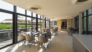 A modern indoor dining area with large windows, tables, and chairs. - La Villa des Vignes (Saint-Émilion)