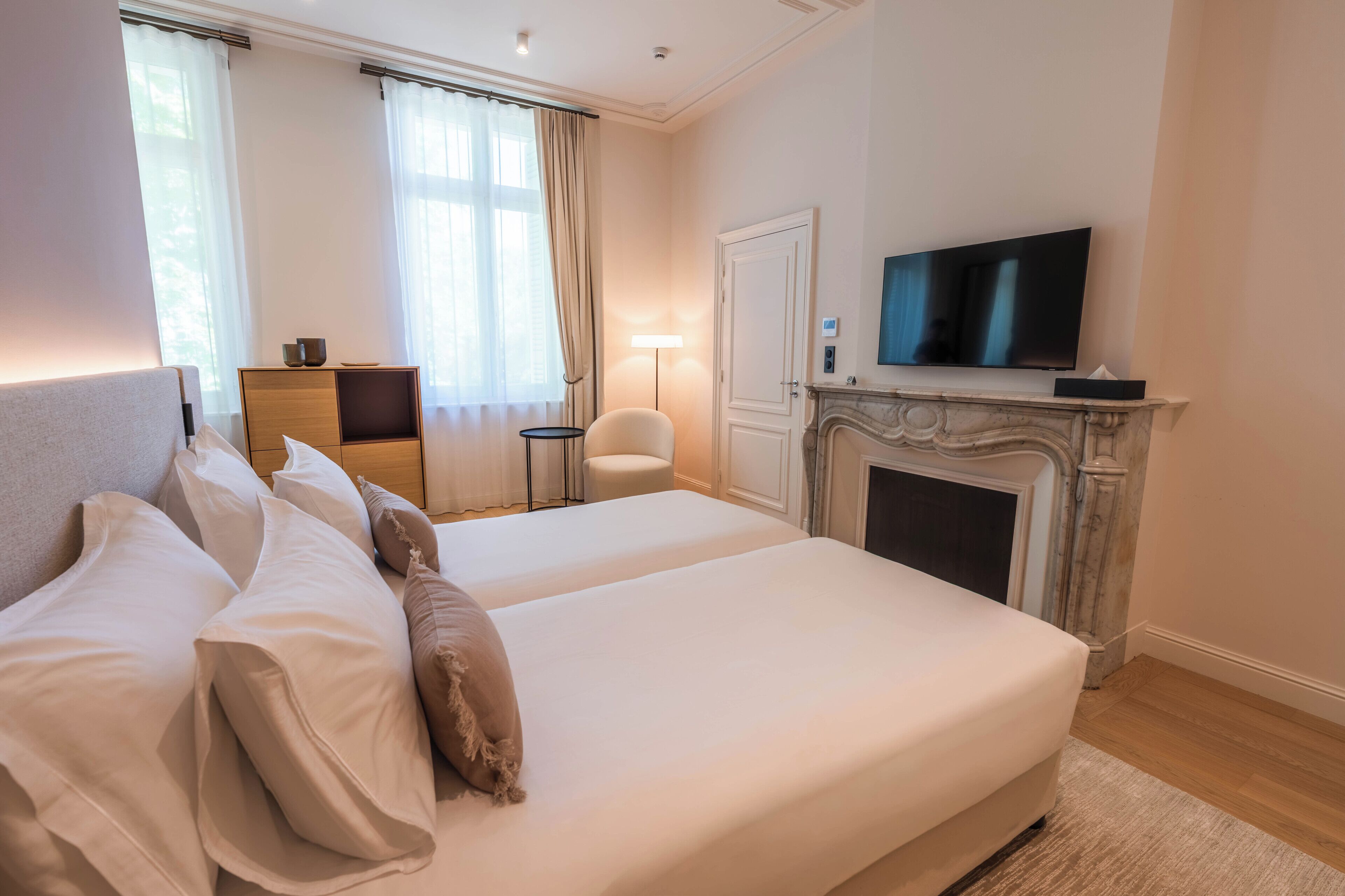 Habitación de hotel con una cama grande, televisor, chimenea y un escritorio con silla.