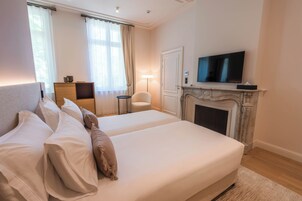 Habitación de hotel con una cama grande, televisor, chimenea y un escritorio con silla.