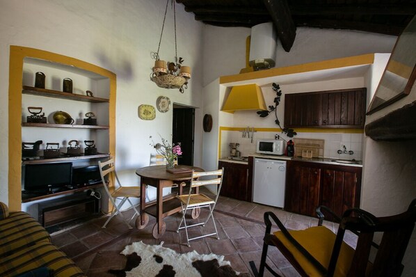 A compact kitchen with a dining area, wooden cabinets, a microwave, and a television.