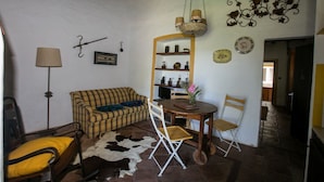 A cozy living room with a sofa, a dining table with chairs, a mirror, and a hanging light fixture. - Sunset Yellow Villa, Avis, Portalegre (Vale do Freixo)