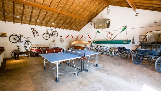 A spacious room with a ping pong table, bicycles, and a boat. - Sunset Yellow Villa, Avis, Portalegre (Vale do Freixo)
