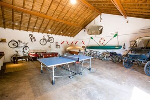 A spacious room with a ping pong table, bicycles, and a boat.