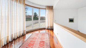 A room with a large window, wooden flooring, and a red patterned rug. - Esmoriz's golden hour with pool (Esmoriz)