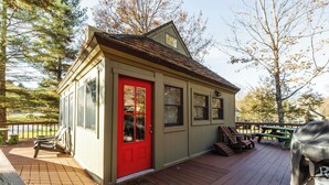 A small wooden building with a red door, a covered barbecue grill, and outdoor seating. - Cozy Updated Cabin, close to towns, A/C (Davis)