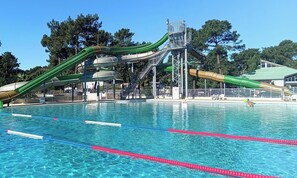 A swimming pool with multiple slides and a lifeguard tower.