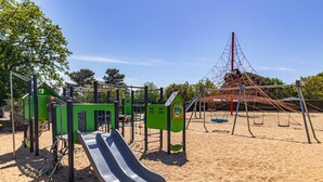 A playground with a slide, climbing structures, and swings. - Mobile Home on Oléron in 5-Star Campsite with Shared Pool (Saint George d'Oleron)