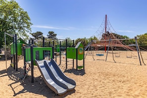 Ein Spielplatz mit Rutsche, Klettergerüsten und Schaukeln.