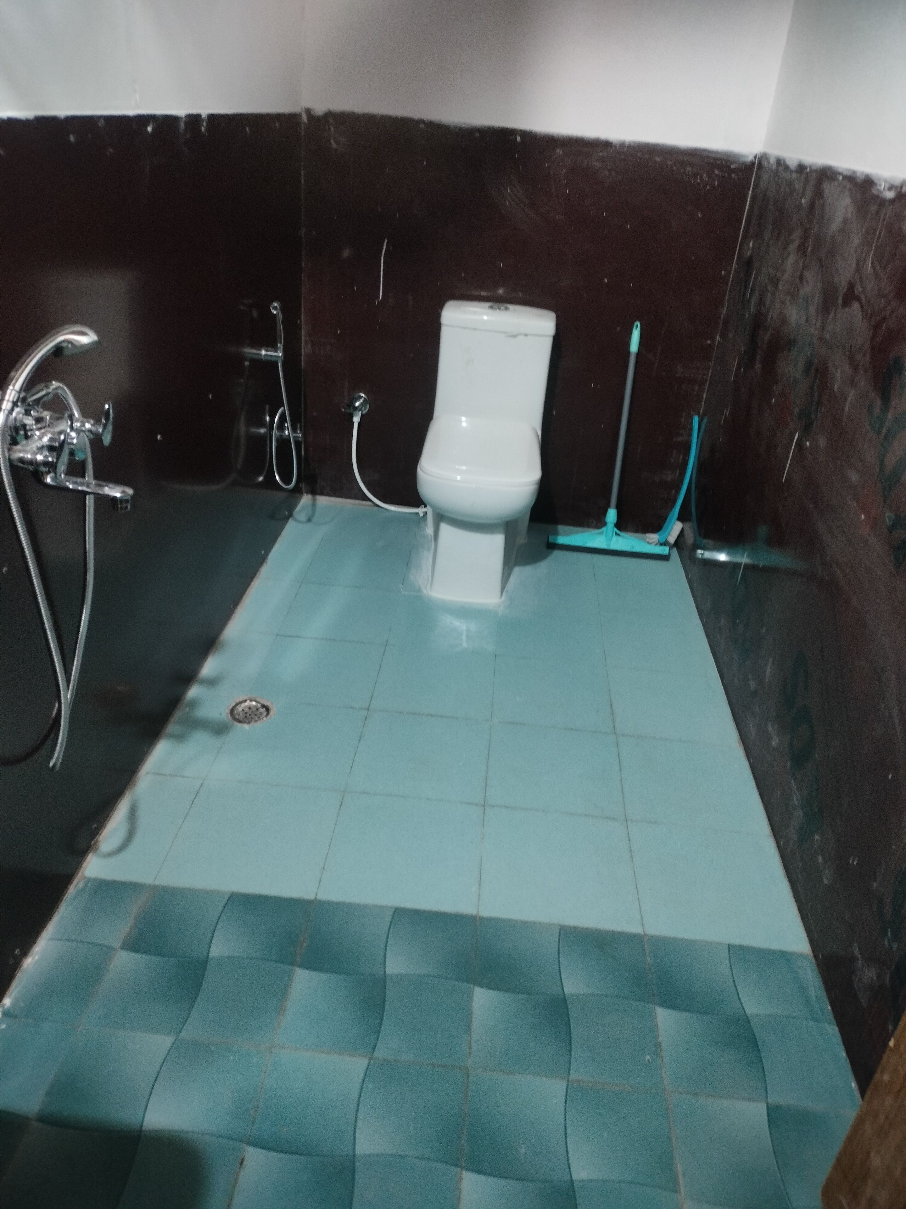 A bathroom with a white toilet, a shower, and a tiled floor.
