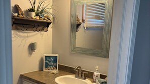 Un bagno con lavandino, specchio, asciugamano e oggetti decorativi.