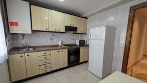 Une cuisine avec des meubles de couleur beige, un réfrigérateur blanc, un four à micro-ondes et une cuisinière.