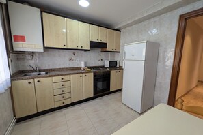 Una cucina con mobili beige, un frigorifero bianco, un forno a microonde e un fornello.