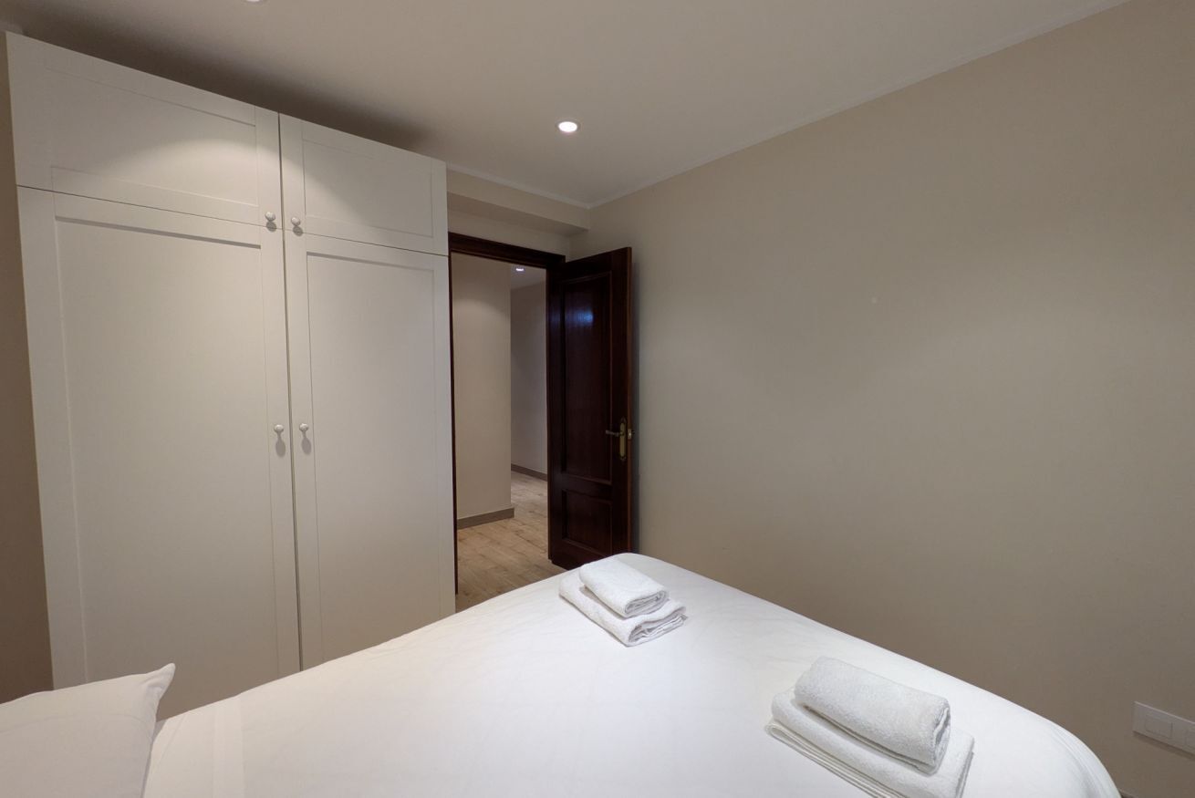 Habitación de hotel con una cama, un armario y una puerta que da a otra habitación.