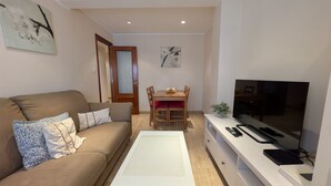 Un salon comprenant un canapé, une table basse, un téléviseur et un coin repas avec des chaises et une table.