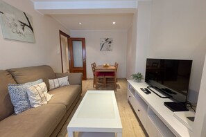 Un soggiorno con divano, tavolino, televisione e zona pranzo con sedie e tavolo.