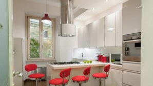 A modern kitchen with white cabinets, a central island with bar stools, a gas stove, and a built-in oven.