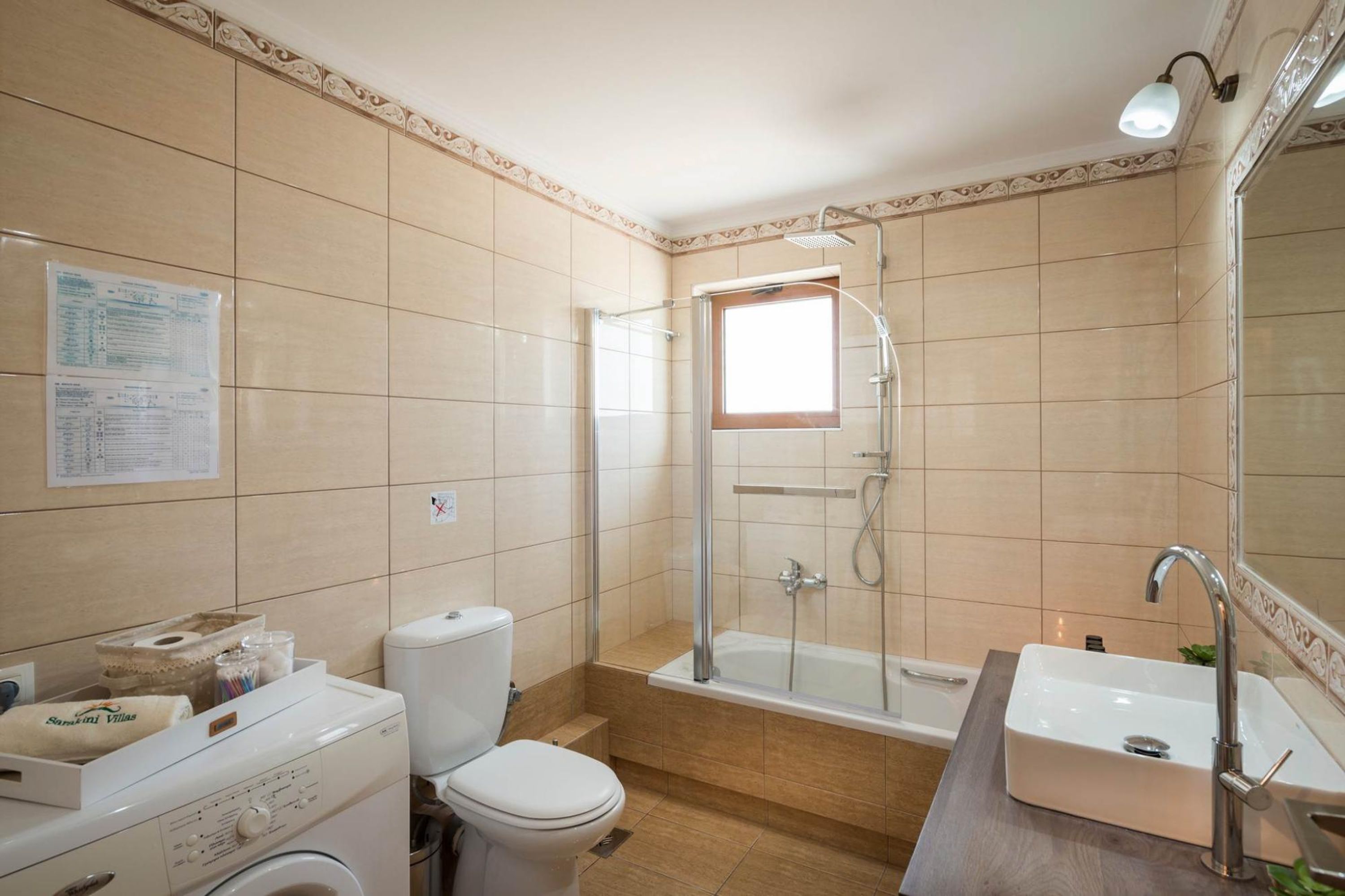 Baño con ducha, inodoro, lavamanos y lavadora.