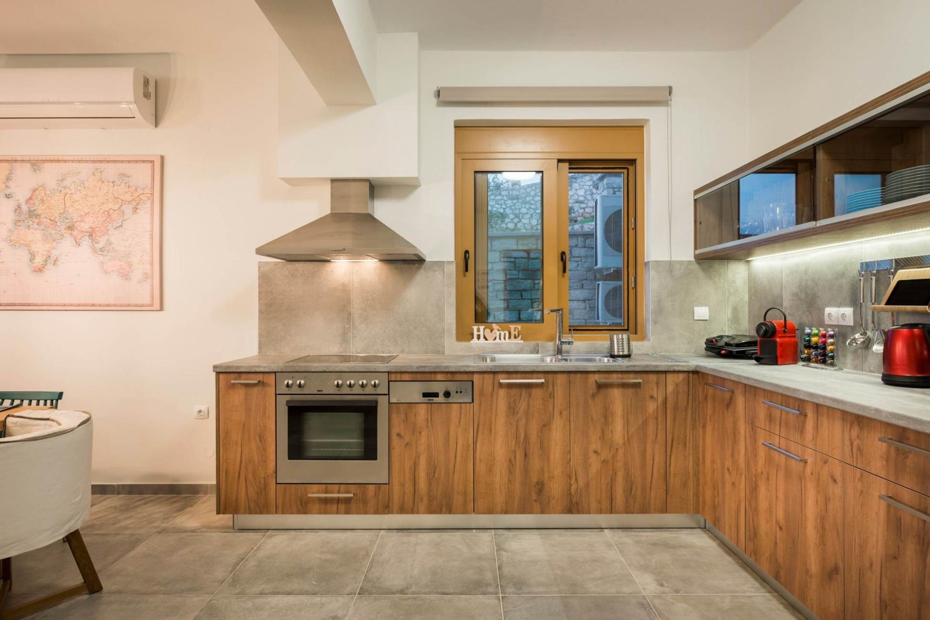 A modern kitchen with wooden cabinets, a built-in oven, and a large window.