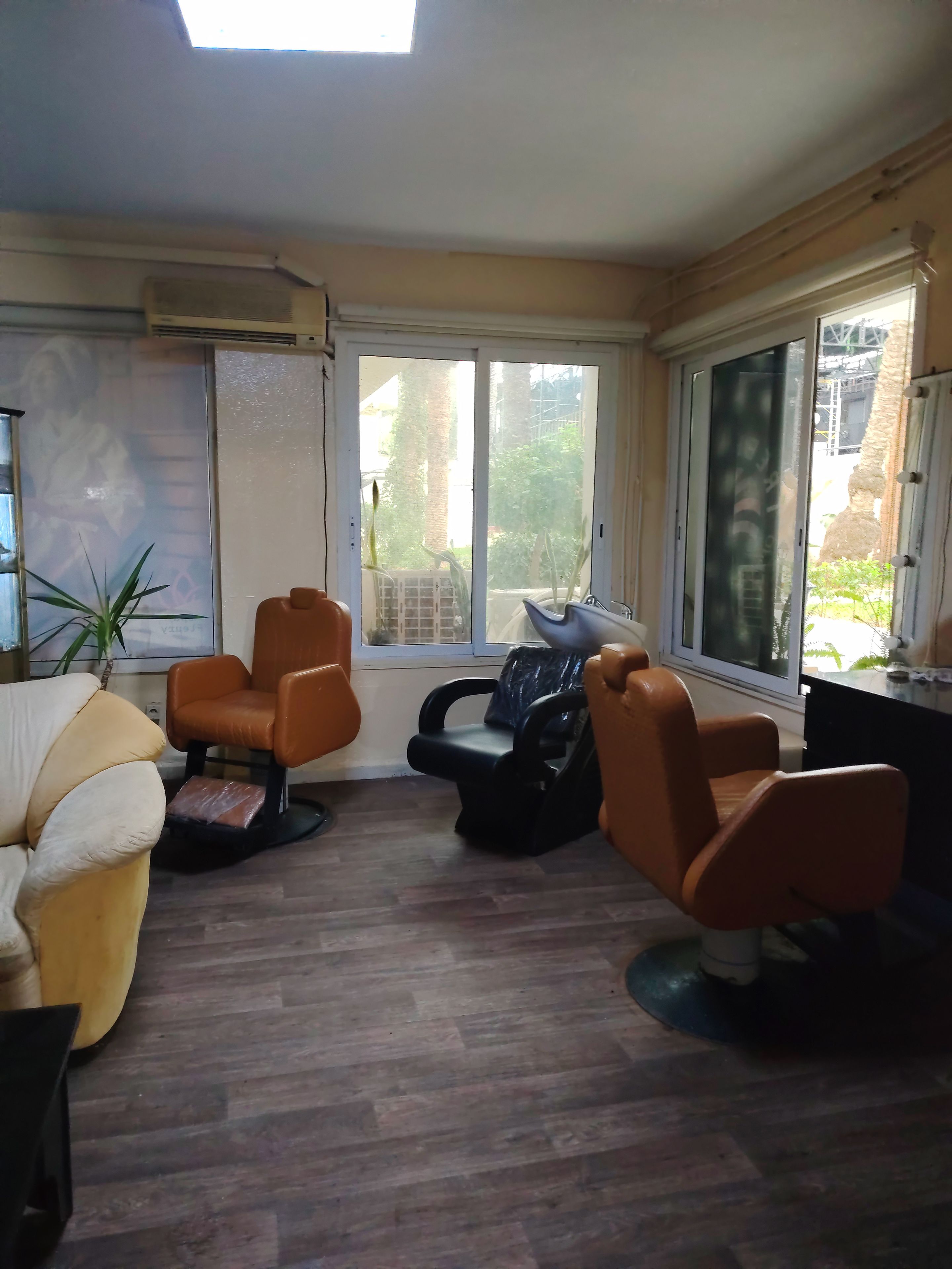 Una stanza con un'ampia porta-finestra scorrevole su un balcone, un divano, due poltrone e un tavolino.
