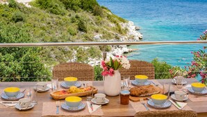 Une table dressée pour le petit-déjeuner, avec vue sur la mer et les collines.