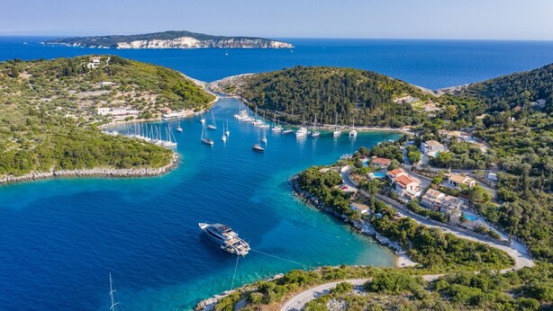 Vue aérienne d’une zone côtière avec un port de plaisance, des bateaux et des bâtiments.