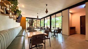 A modern interior with a sofa, dining tables, chairs, and a staircase leading to an outdoor area.