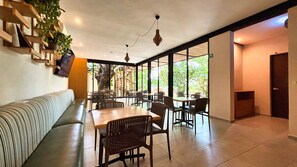 A modern interior with a sofa, dining tables, chairs, and a staircase leading to an outdoor area. - Loft with Pool and King Size Bed in Montejo (Mérida)