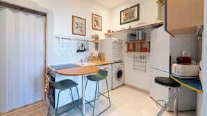 Een kleine keuken met een eethoek, een wasmachine en een koffieapparaat.