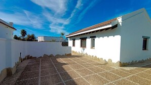 A white building with a tiled patio and a clear blue sky.