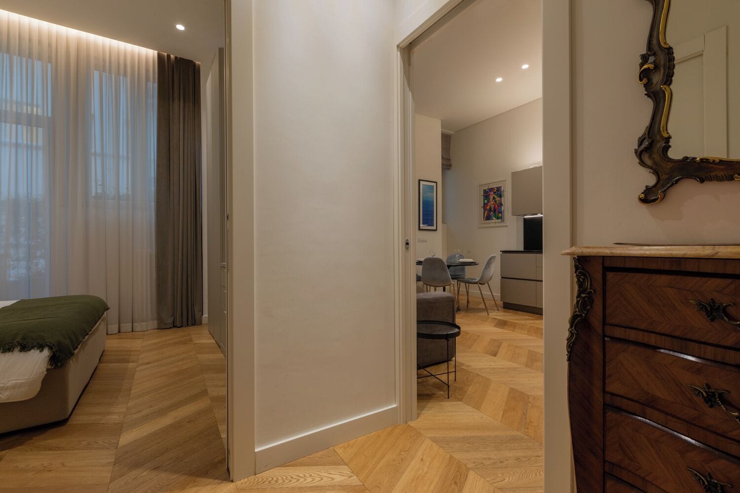 Un dormitorio moderno con cama, cómoda y zona de comedor con sillas y mesa.