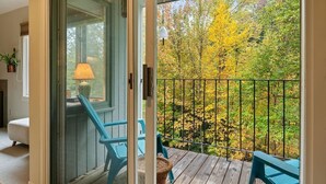 Une pièce dotée d’une porte-fenêtre coulissante donnant sur un balcon avec vue sur le feuillage automnal.