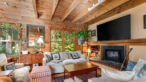 A cozy living room with a fireplace, wooden beams, a television, and comfortable seating.