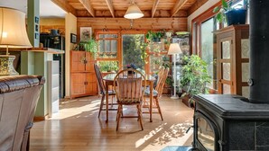 A cozy kitchen with wooden beams, a dining table with chairs, and a fireplace.