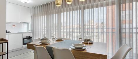 A modern dining area with a wooden table, white chairs, and hanging pendant lights.