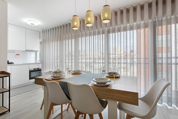 A modern dining area with a wooden table, white chairs, and hanging pendant lights.