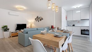 A modern living space with a dining area, kitchen, and seating area. - Coral Beach Apartment (Figueira da Foz)