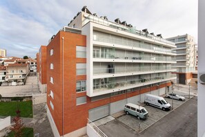 Een meerlaags gebouw met een parkeerplaats, een overdekt terras en een duidelijke trap die naar de ingang leidt.