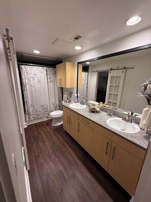 Un baño moderno con dos lavamanos, inodoro y zona de ducha.