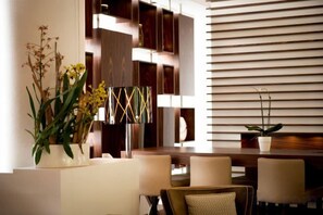 Un interior moderno con una zona de comedor, una planta en maceta y una pared con líneas horizontales.