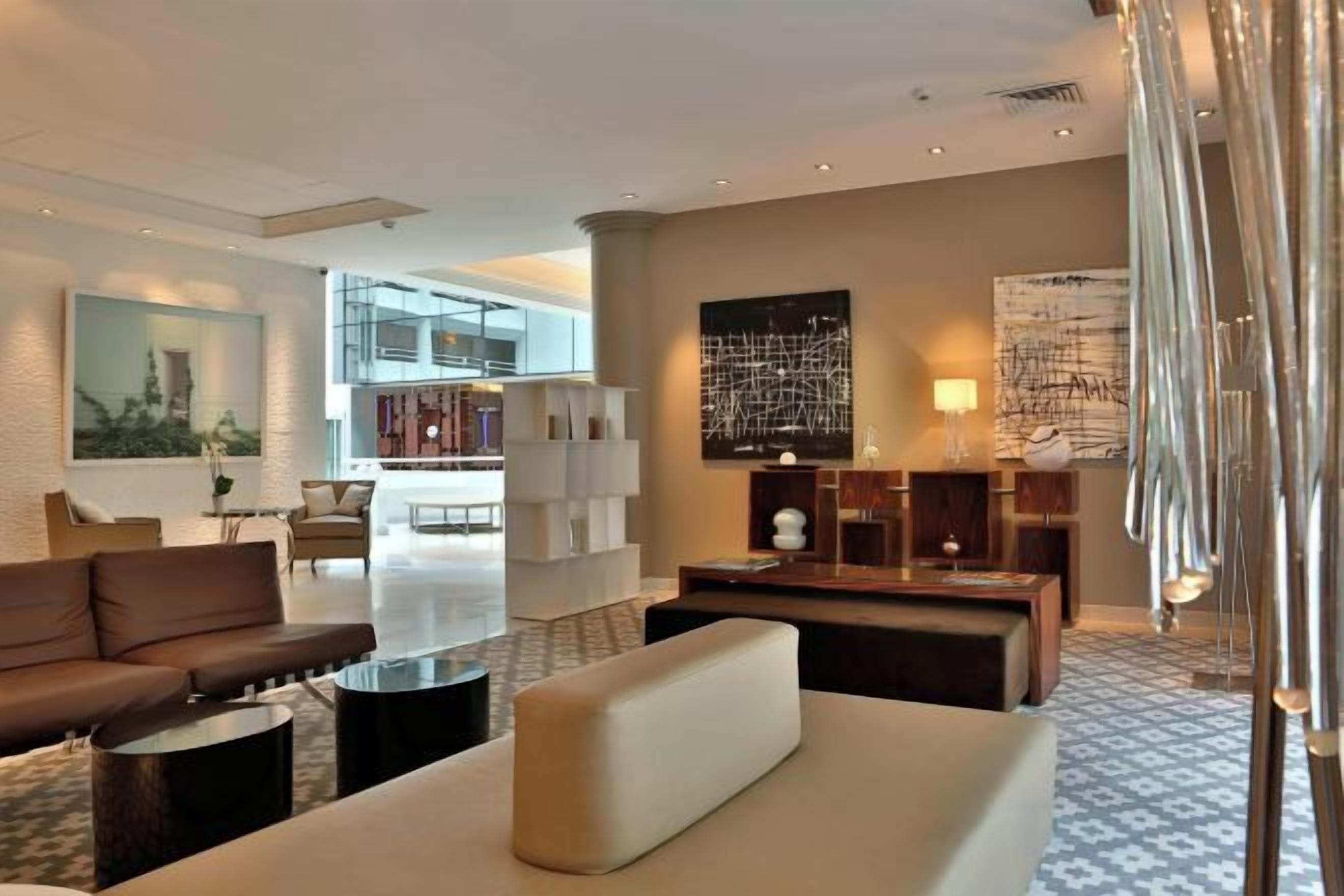A modern hotel lobby with a sofa, coffee table, and a large abstract painting.