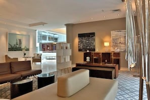 A modern hotel lobby with a sofa, coffee table, and a large abstract painting.