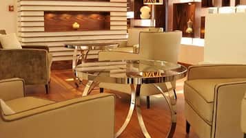 Una sala moderna con una mesa redonda de vidrio, dos sillones, un sofá y un televisor de pantalla plana montado en una pared de madera.