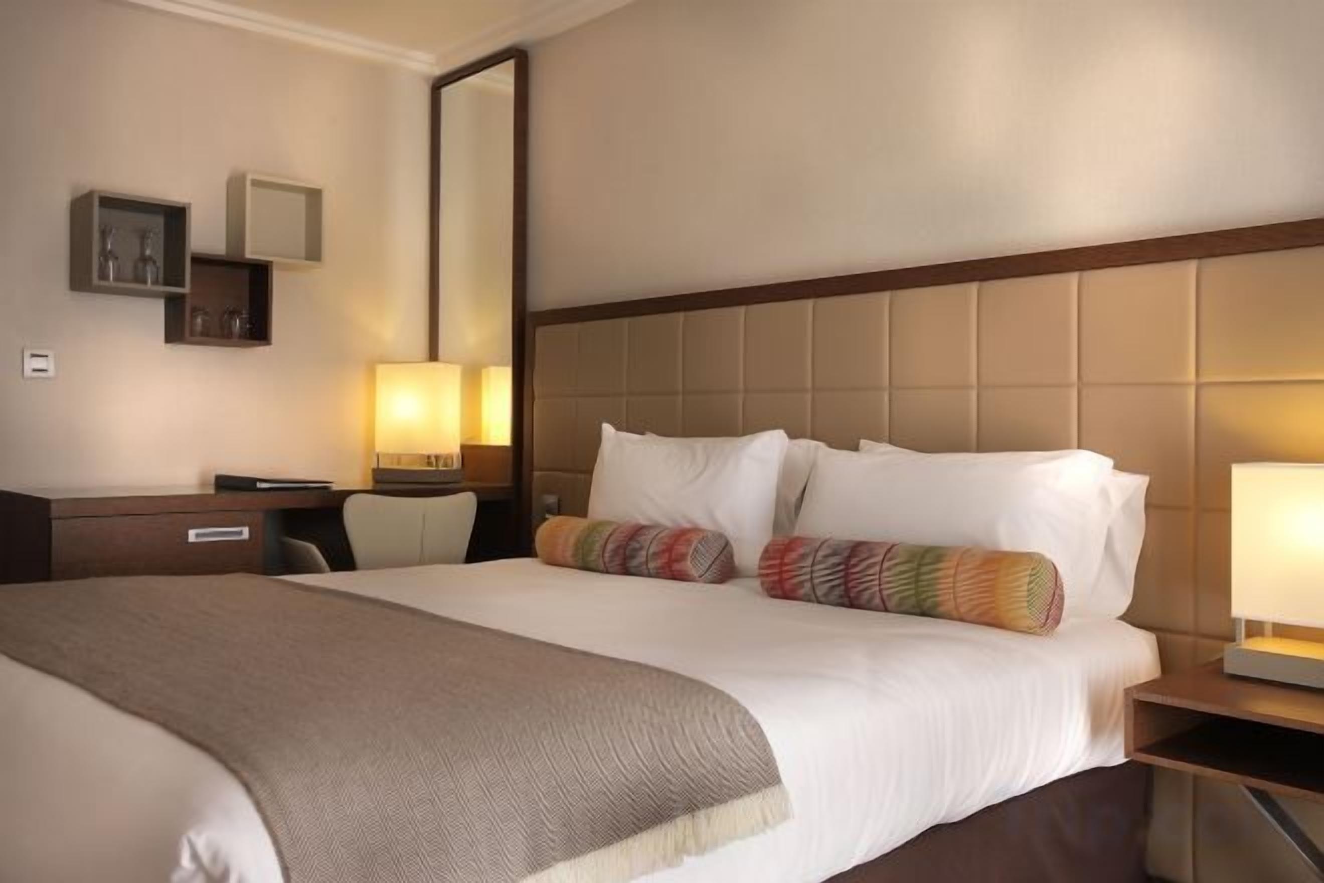 A hotel room with a large bed, bedside tables, a desk, and a chair.