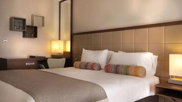 A hotel room with a large bed, bedside tables, a desk, and a chair.