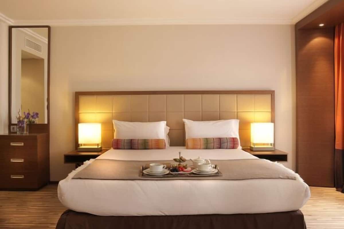 Quarto de hotel com uma cama grande, duas mesas de cabeceira, um aparador e um espelho.